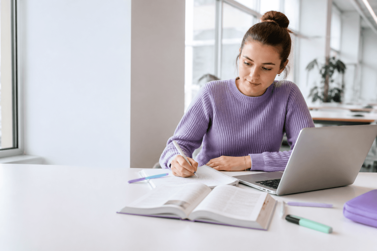 Student die met een laptop en studieboeken werkt